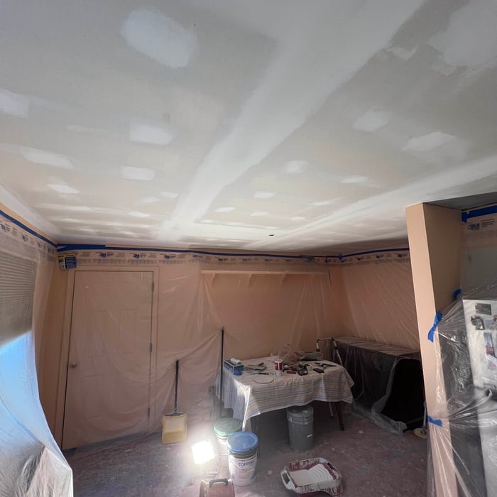 New drywall ceiling being finished, with flooring and furniture protected